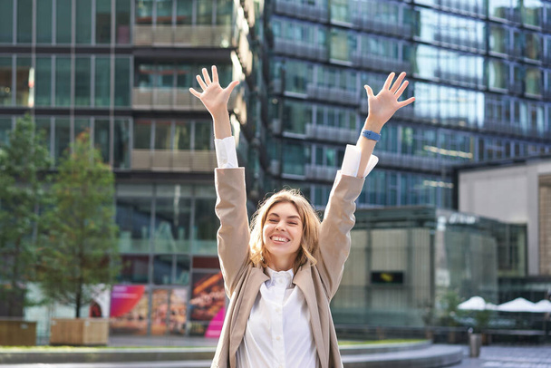 Corporate Frau feiert ihren Sieg draußen auf der Straße. Glückliche Geschäftsfrau hebt die Hände und triumphiert vor Aufregung. - Foto, Bild