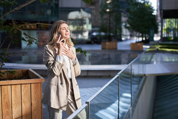 Sfrustrowana korporacyjna kobieta stojąca na ulicy i mająca trudny telefon, słyszy złe wieści z rozmowy telefonicznej. - Zdjęcie, obraz