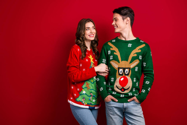 Photo of joyful sweet husband wife dressed ugly jumpers enjoying romantic feelings empty blank space isolated on red color background. - Foto, Imagen