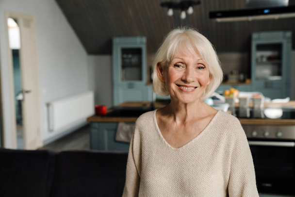 Happy mature woman smiling and looking at camera in home - Photo, Image