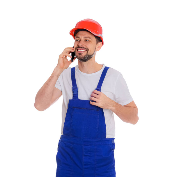 Professional repairman in uniform talking on phone against white background - Foto, afbeelding