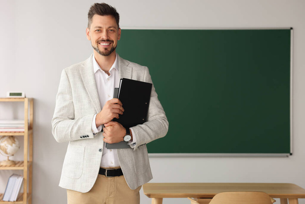 Happy teacher with stationery in classroom. Space for text - Fotografie, Obrázek