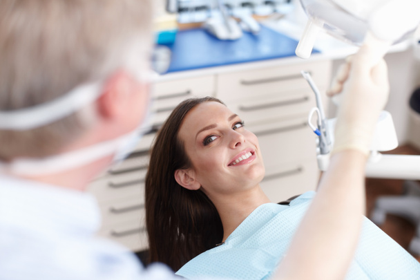 Χαμογελαστός ασθενής με οδοντίατρο. Υψηλή οπτική γωνία του ασθενούς χαμογελώντας με οδοντίατρο στην κλινική - Φωτογραφία, εικόνα