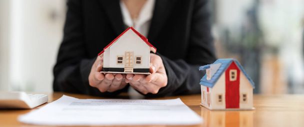 Hausmodell mit Immobilienmakler und Kunde im Gespräch für Vertrag zum Kauf von Haus, Versicherung oder Darlehen Immobilien Hintergrund. - Foto, Bild