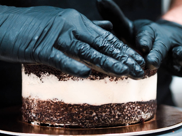 Projektant tortu kucharskiego przygotowuje warstwową kremową bazę tortową do mrożonej dekoracji i polewy - Zdjęcie, obraz