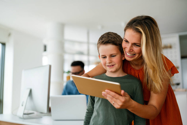 Home schooling social distance e-learning online education concept. Happy school boy using tablet at home. - Fotó, kép