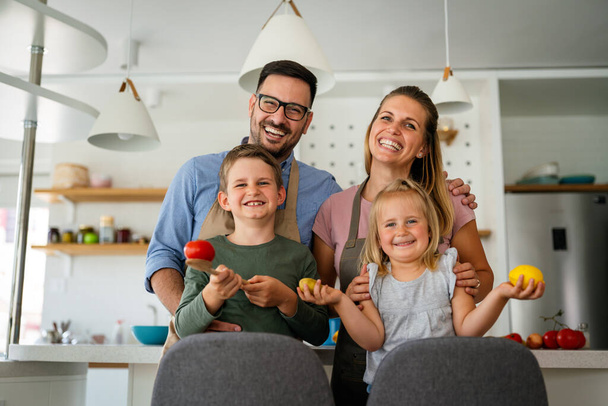 Happy young family preparing healthy food together in kitchen. People happiness cooking concept - Photo, Image