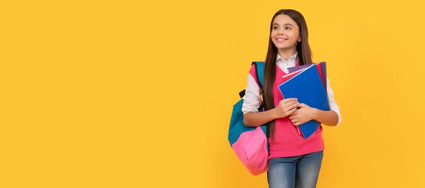 gelukkig tiener schoolmeisje met rugzak en copybook over gele achtergrond, kennis. Banner van schoolmeisje student. Schoolmeisje scholier portret met kopieerruimte - Foto, afbeelding