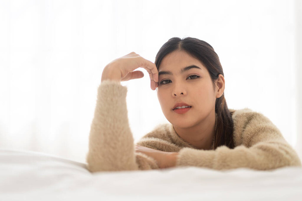 Portrait of smiling cheerful beautiful pretty asian woman clean fresh healthy white skin posing smile in pajamas white clothes.Girl felling relax and enjoy time on the bed at home.asia beauty - 写真・画像