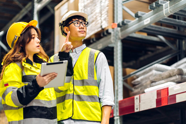 Asian two engineer team shipping order detail on tablet check goods and supplies on shelves with goods background inventory in factory warehouse.logistic industry and business export - 写真・画像