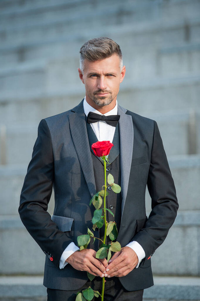 special occasion concept. charismatic man with rose for special occasion. tuxedo man outdoor at special occasion. - Foto, afbeelding