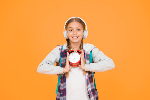 hipster girl manage time correctly. schoolgirl casual style hold retro alarm clock. autumn education period. child listen music earphones. time management in childhood. exam deadline concept. - 写真・画像