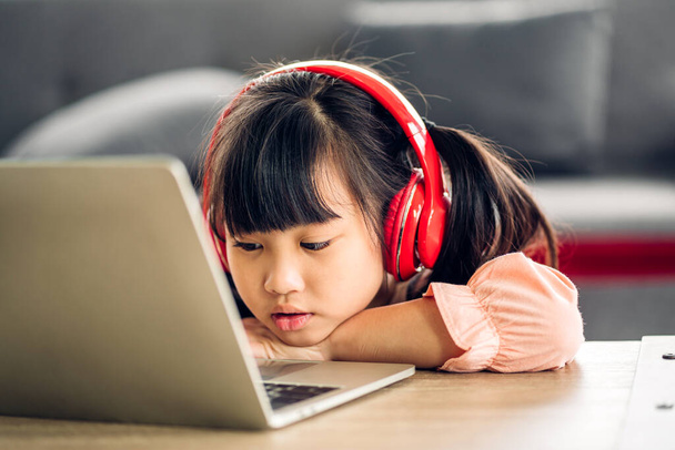 Шкільна маленька студентська дівчинка вчиться і дивиться на ноутбук комп'ютер робить домашнє завдання, вивчаючи знання з онлайн-навчанням e-learning system.childs video conference with teacher home
 - Фото, зображення