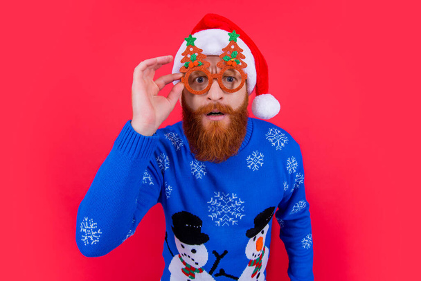 christmas party. curious man in party glasses at christmas. santa man at chirstmas party isolated on red background. - Photo, image