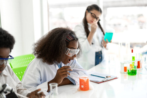 Bir grup genç öğrenci fen ve çalışma öğreniyor, kimya bilimi deneyi yapıyor ve deney laboratuarı sınıfında el ele deney tüpü tutuyor. - Fotoğraf, Görsel