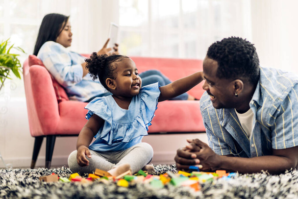 Portret szczęśliwej miłości czarny rodzina afrykański ojciec i matka z małą dziewczynką uśmiechnięta aktywność uczyć się i umiejętności mózgu gra z zabawką budować drewniane klocki gra edukacyjna w domu - Zdjęcie, obraz
