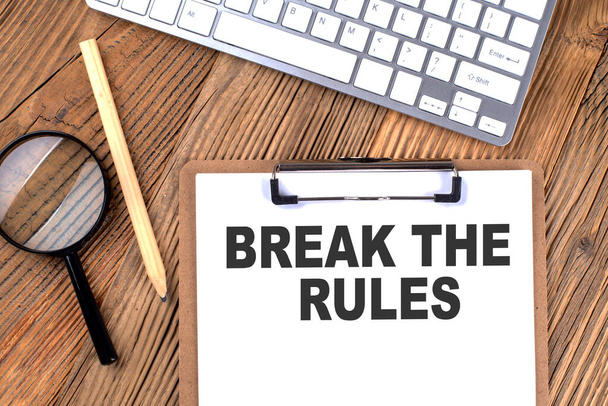 BREAK THE RULES text on paper clipboard with magnifier and keyboard on a wooden background - Photo, Image
