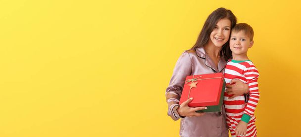 Γυναίκα και ο γιος της με χριστουγεννιάτικο δώρο σε κίτρινο φόντο με χώρο για κείμενο - Φωτογραφία, εικόνα