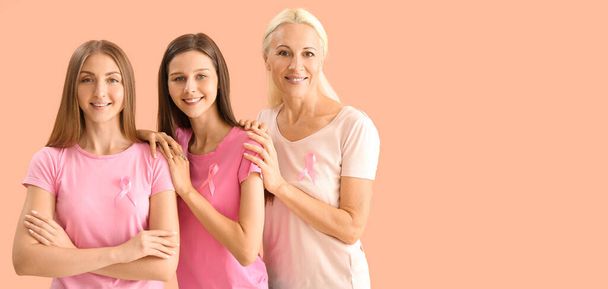 Beautiful women with pink ribbons on beige background with space for text. Breast cancer awareness concept - Фото, изображение