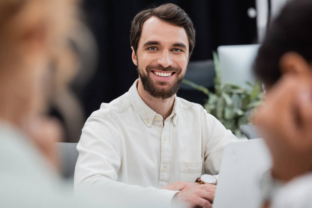bearded businessman looking at camera in office on blurred foreground - Foto, immagini