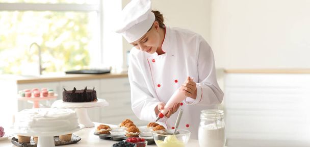 Dolcificante femminile che cucina gustosi cupcake in cucina - Foto, immagini