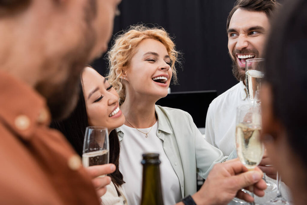 Excited interracial business people toasting with champagne in office  - Photo, Image