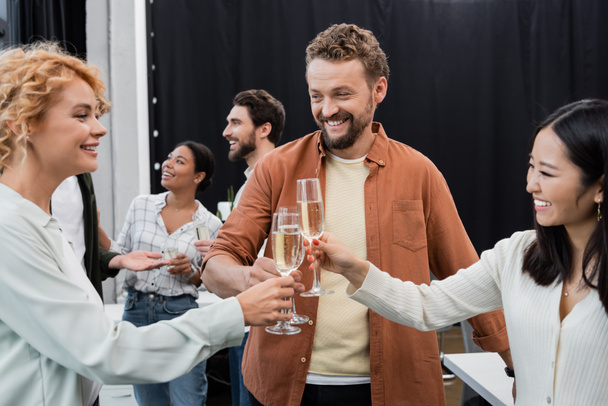 Cheerful interracial business people toasting and holding champagne in office  - Foto, immagini