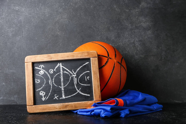 Chalkboard with drawn scheme of basketball game, uniform and ball on dark background - Photo, Image