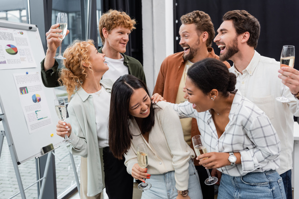 Veselý multietnický byznys lidé mluví a drží sklenice šampaňského v kanceláři  - Fotografie, Obrázek