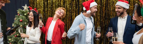 Allegri uomini d'affari interrazziale con champagne ballare e parlare durante la celebrazione di Natale, striscione  - Foto, immagini
