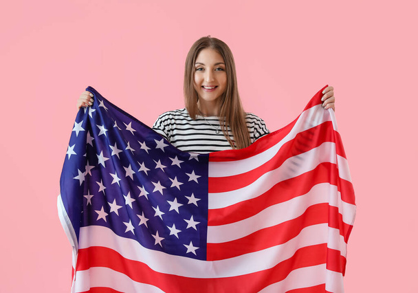 ピンクの背景にアメリカの旗を持つ美しい女性 - 写真・画像