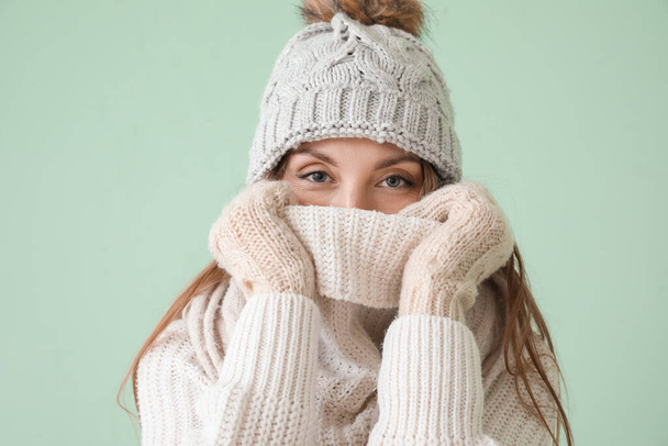 Young woman in warm hat and scarf on green background - Photo, Image