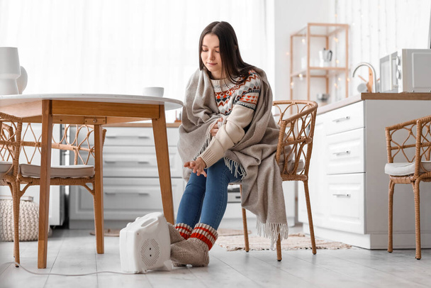 Mladá žena v pletené ponožky oteplování v blízkosti elektrického ventilátoru doma - Fotografie, Obrázek