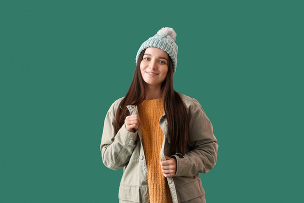 Młoda kobieta w ciepłym kapeluszu i kurtce na zielonym tle - Zdjęcie, obraz