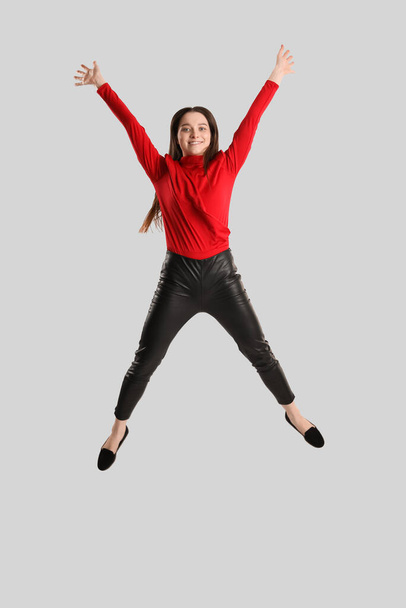 Junge brünette Frau in Lederhosen springt auf grauem Hintergrund - Foto, Bild