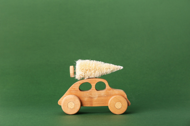 Toy car with Christmas tree on green background - Foto, afbeelding