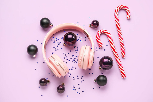 Composizione con cuffie moderne, palline di Natale e bastoncini di zucchero su sfondo a colori - Foto, immagini