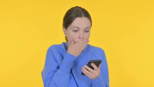 Casual γυναίκα απώλεια για Smartphone σε κίτρινο φόντο  - Πλάνα, βίντεο