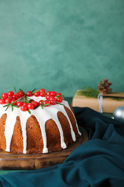 Wooden board with delicious Christmas cake on green background, closeup - Fotó, kép