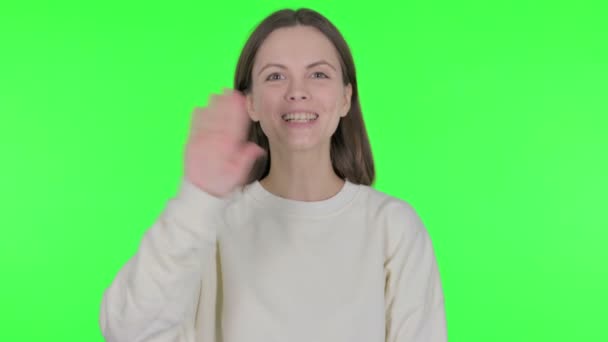 Casual vrouw zwaaien hand om hallo te zeggen op groene achtergrond  - Video