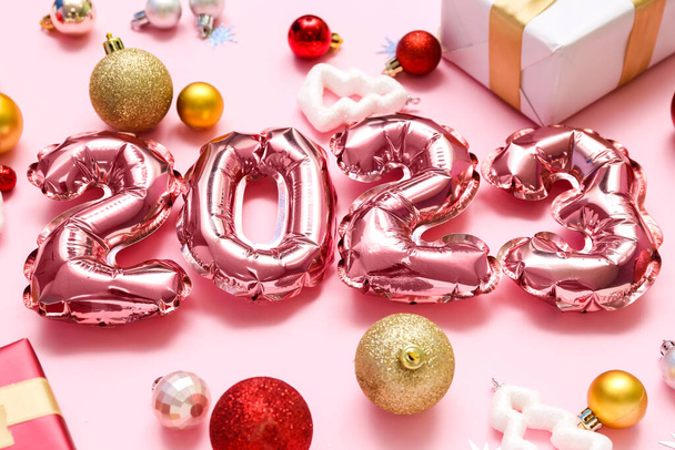 Figure 2023 made of foil balloons with Christmas decor on pink background, closeup - Photo, Image