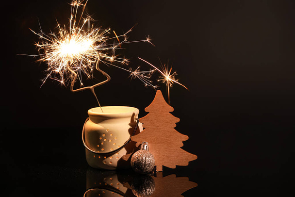 Burning sparklers and Christmas decor on dark background - Фото, зображення