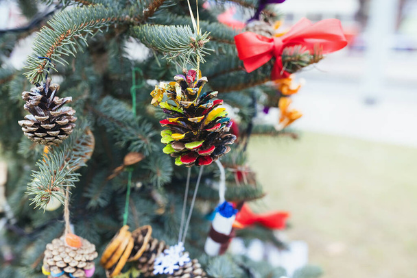 Malovaný borový kužel na vánočním stromečku. Diy dekorace nápady pro děti. Životní prostředí, recyklace, recyklace a koncepce nulového odpadu. Selektivní zaměření, venkovní zázemí bez sněhu, kopírovací prostor - Fotografie, Obrázek