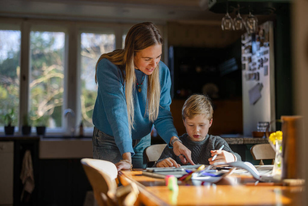 Мати допомагає сину з домашнім завданням вдома
 - Фото, зображення