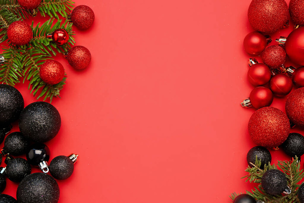 Samenstelling met mooie kerstballen en sparren takken op rode achtergrond - Foto, afbeelding