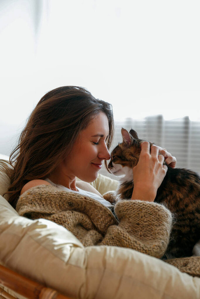 Portrait of young woman holding cute norwegian cat with green eyes. Female hugging her cute long hair kitty. Background, copy space, close up. - Foto, imagen