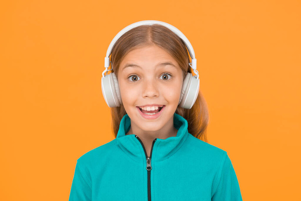 Happy song makes her smile. Happy small girl listen to music on yellow background. Little child enjoy song playing in headphones. Smile on happy face. Music has happy emotions. - Valokuva, kuva