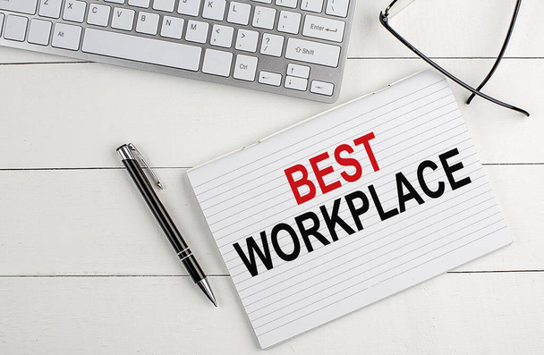 BEST WORKPLACE text on notebook with keyboard , pen glasses on a white wooden background - Photo, Image