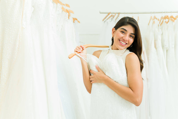 Splendida donna messicana guardando la fotocamera sorridente durante lo shopping per un bellissimo abito da sposa  - Foto, immagini
