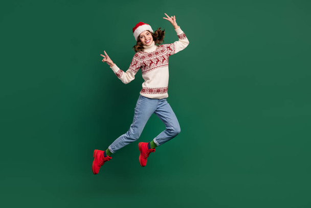 Full size portrait of overjoyed crazy girl jumping demonstrate v-sign isolated on green color background. - Foto, imagen